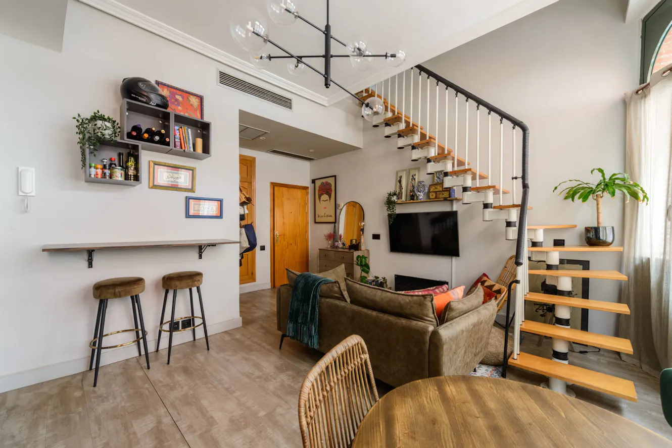 Living room with brown sectional sofa, wall-mounted TV, modern floating staircase with wood treads, bar seating area, and dining table