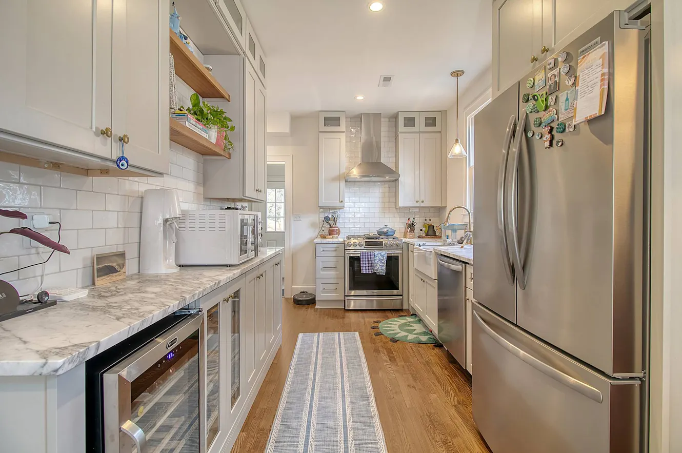 Kitchen with white shaker cabinets, marble countertops, stainless steel appliances, subway tile backsplash, and hardwood flooring
