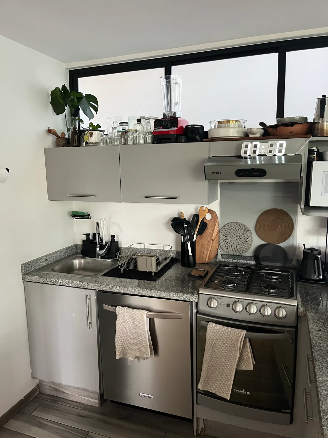 Kitchen with gray cabinets, granite countertops, stainless steel appliances, gas stove, sink, and large window with natural light
